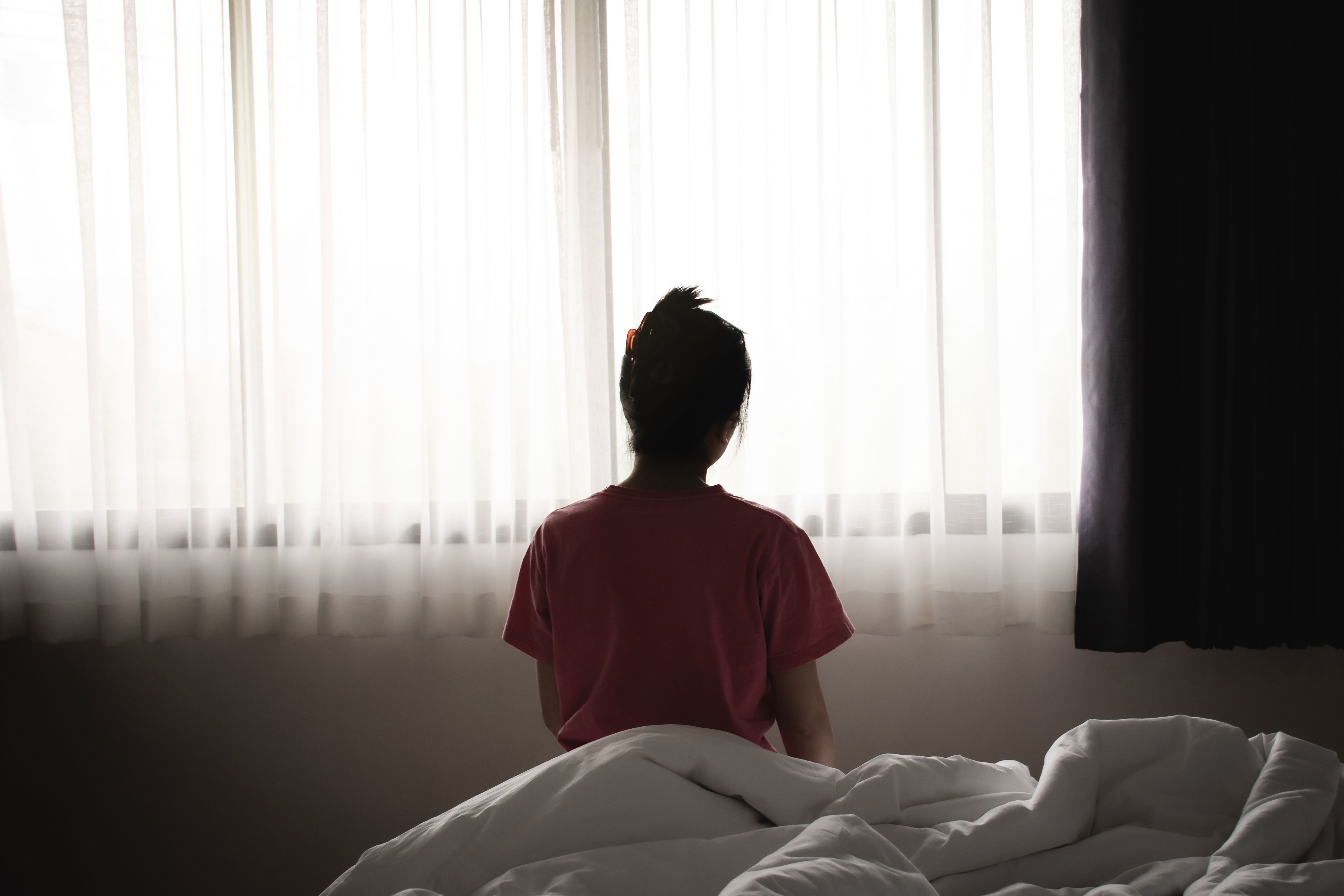Young person sitting in a peaceful private bedroom of a sober living home, symbolizing reflection and positive change in recovery.