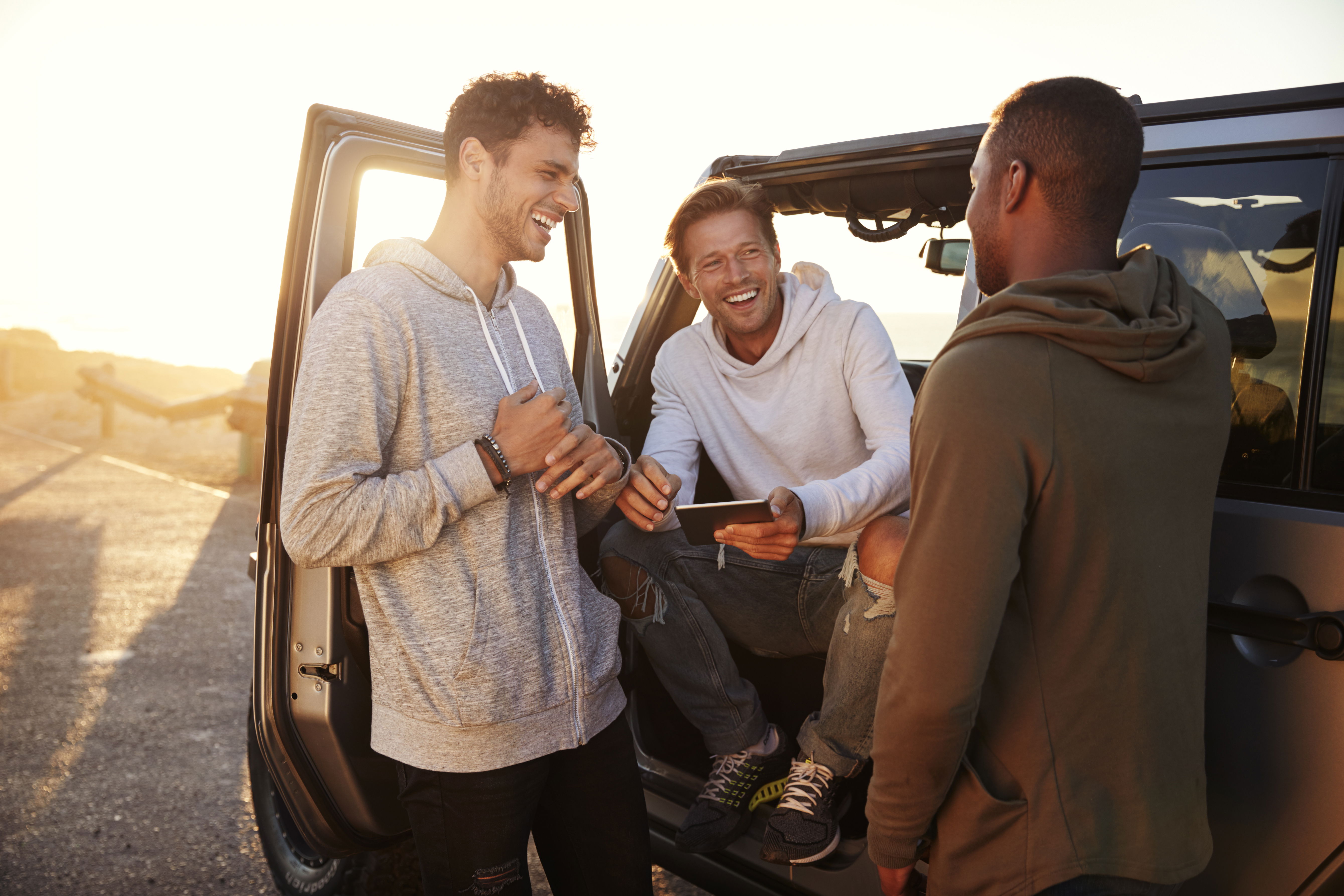 Group of guy friends hanging outside of a jeep preparing for a beach day.