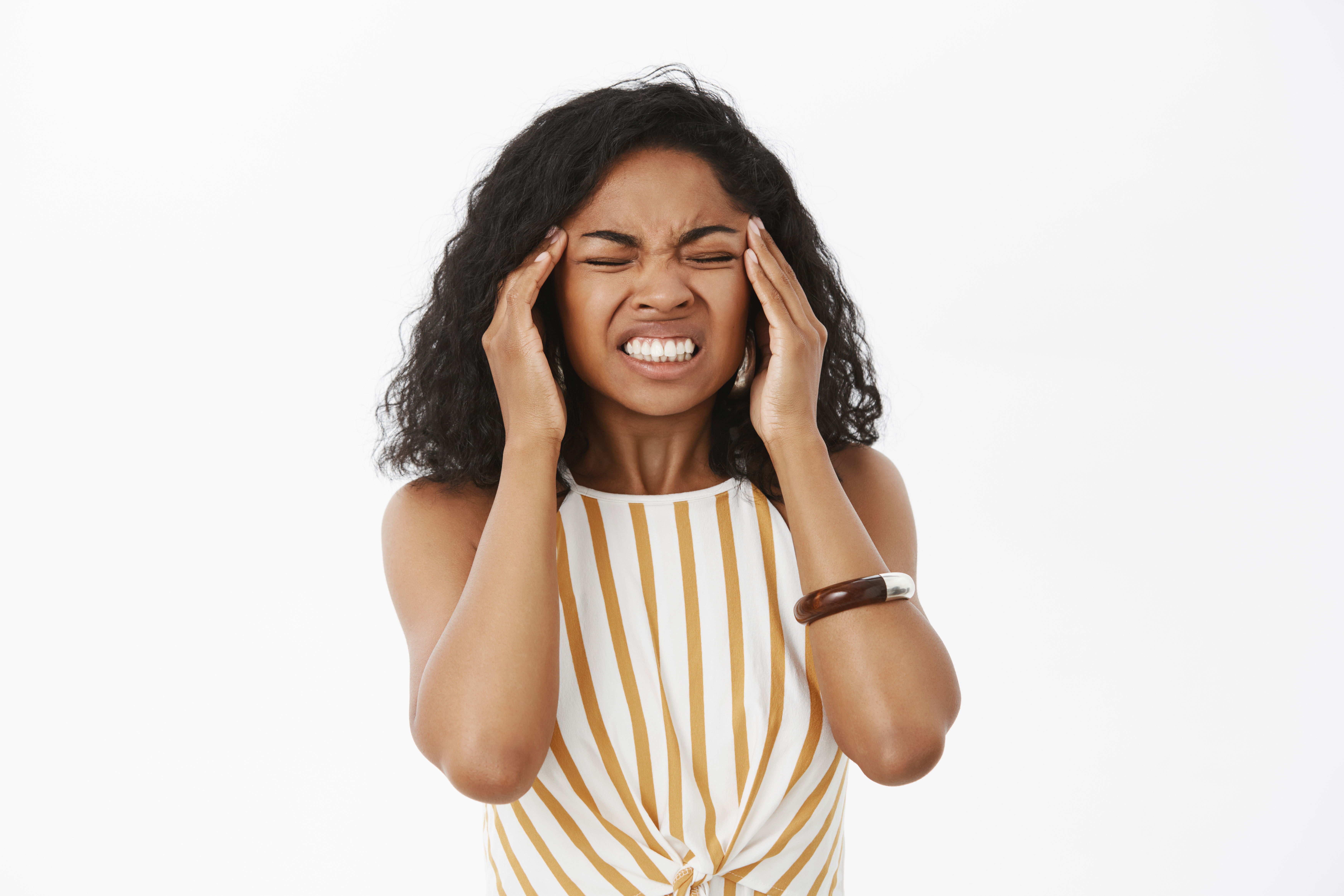 Woman with a distressed expression, holding her head and clenching her teeth in pain