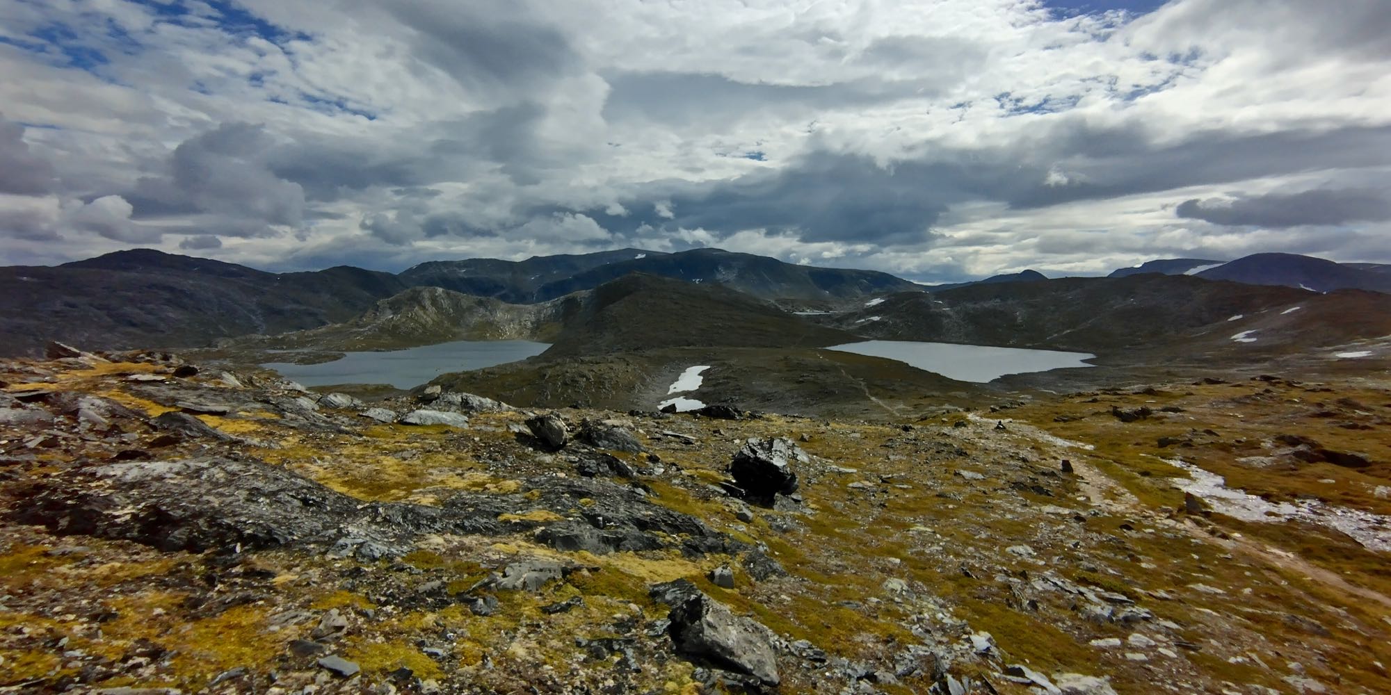 Tunturilaakso, jossa näkyy kaksi pientä järveä. Vaelluspolku kulkee niiden välistä kapeaa kannasta.