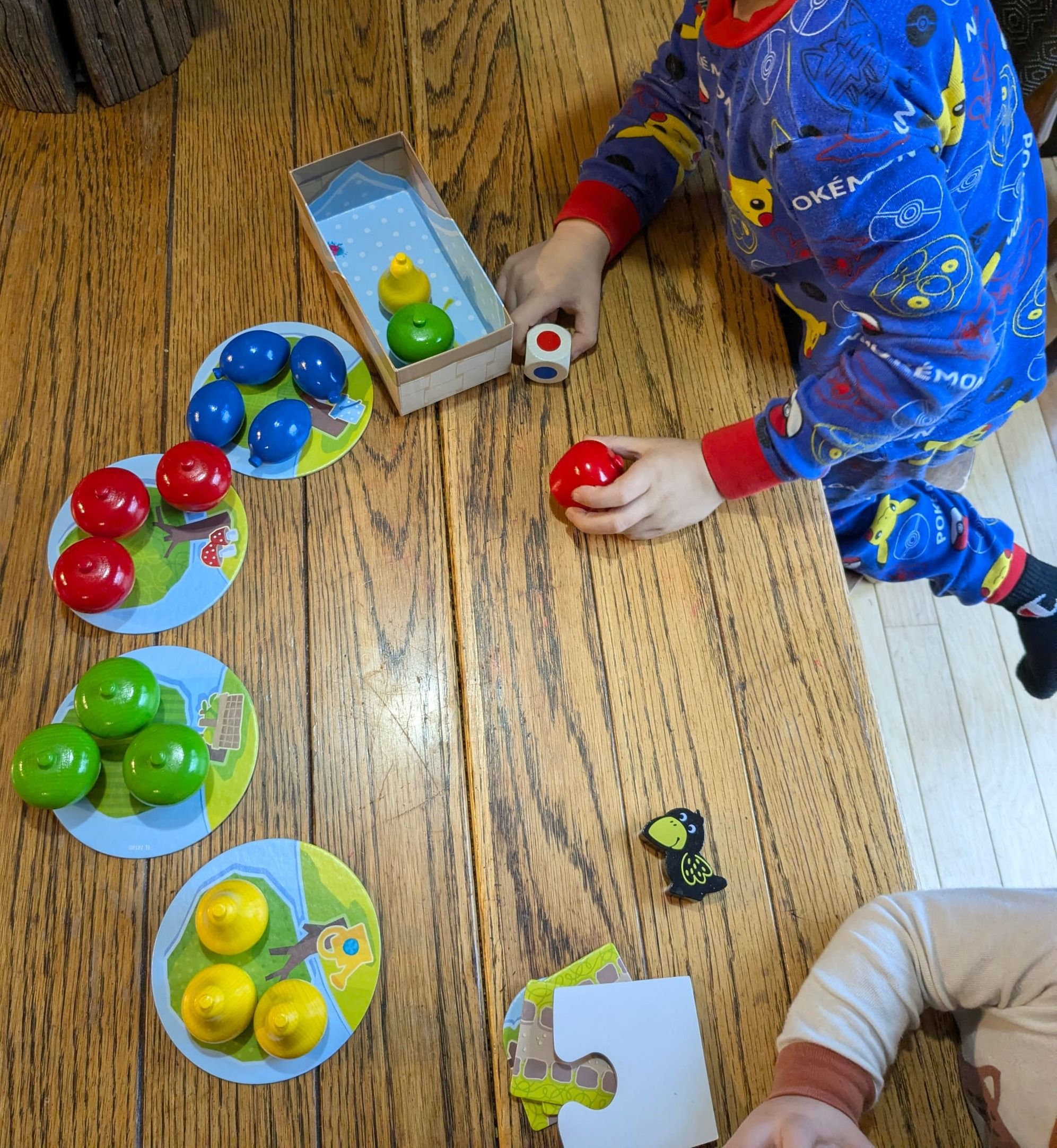 A young child playing First Orchard with wooden fruit playing pieces