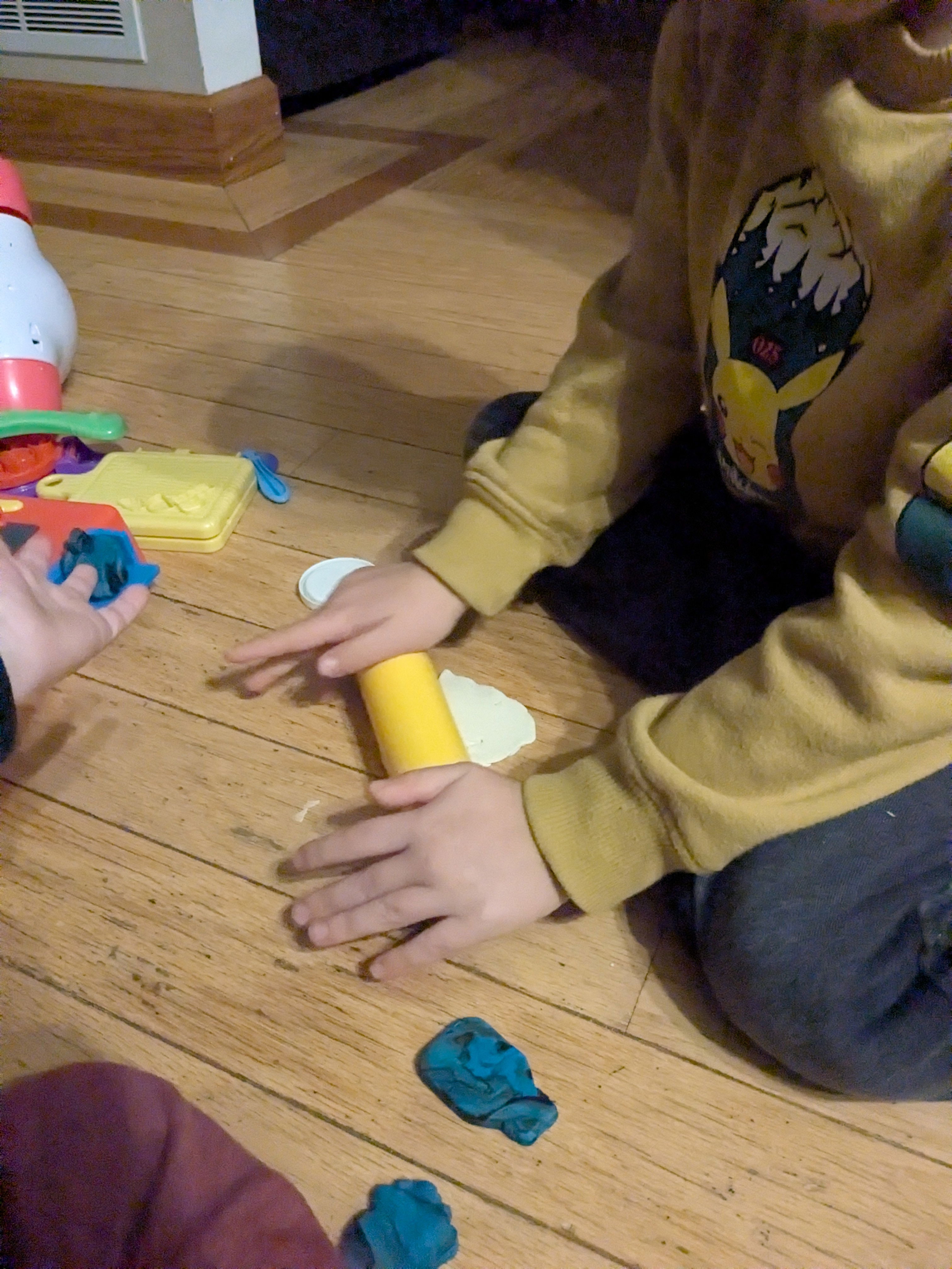 A young boy using a rolling pin over white play doh