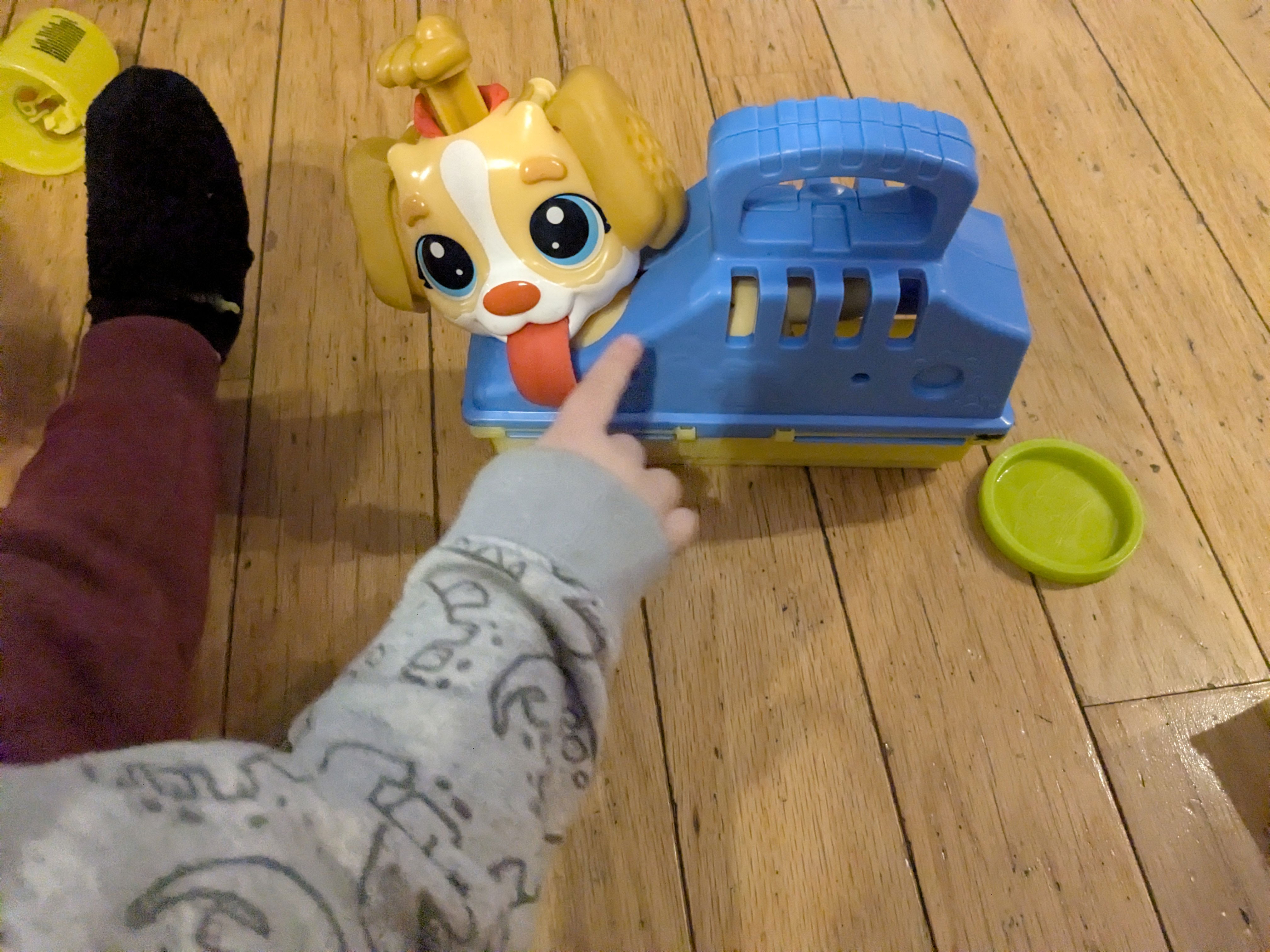 A play puppy in a carrier with a play doh tongue sticking out