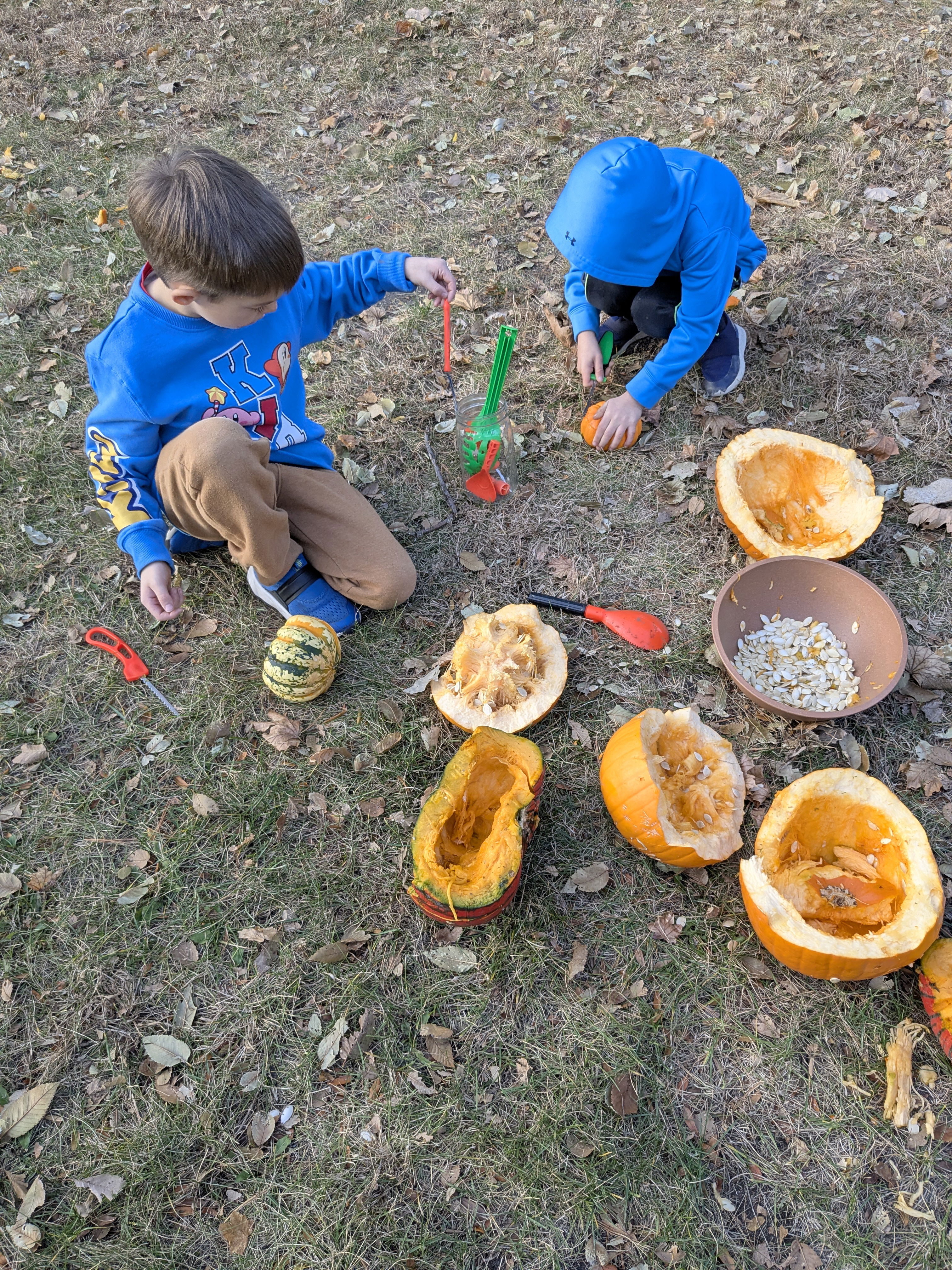 Two little boys breaking apart pumpkins for composting