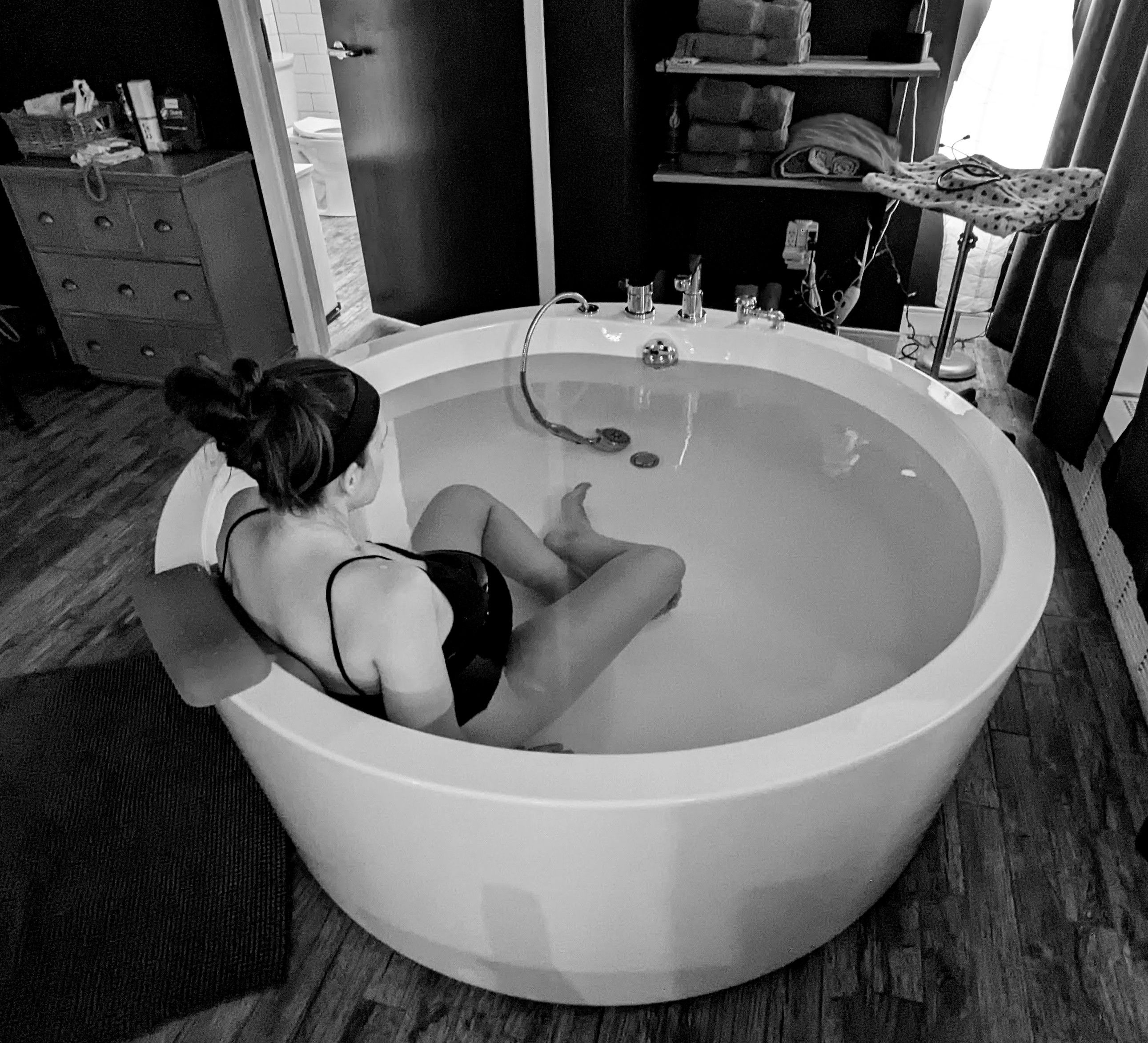 A woman sitting peacefully in a birthing tub, black and white photo