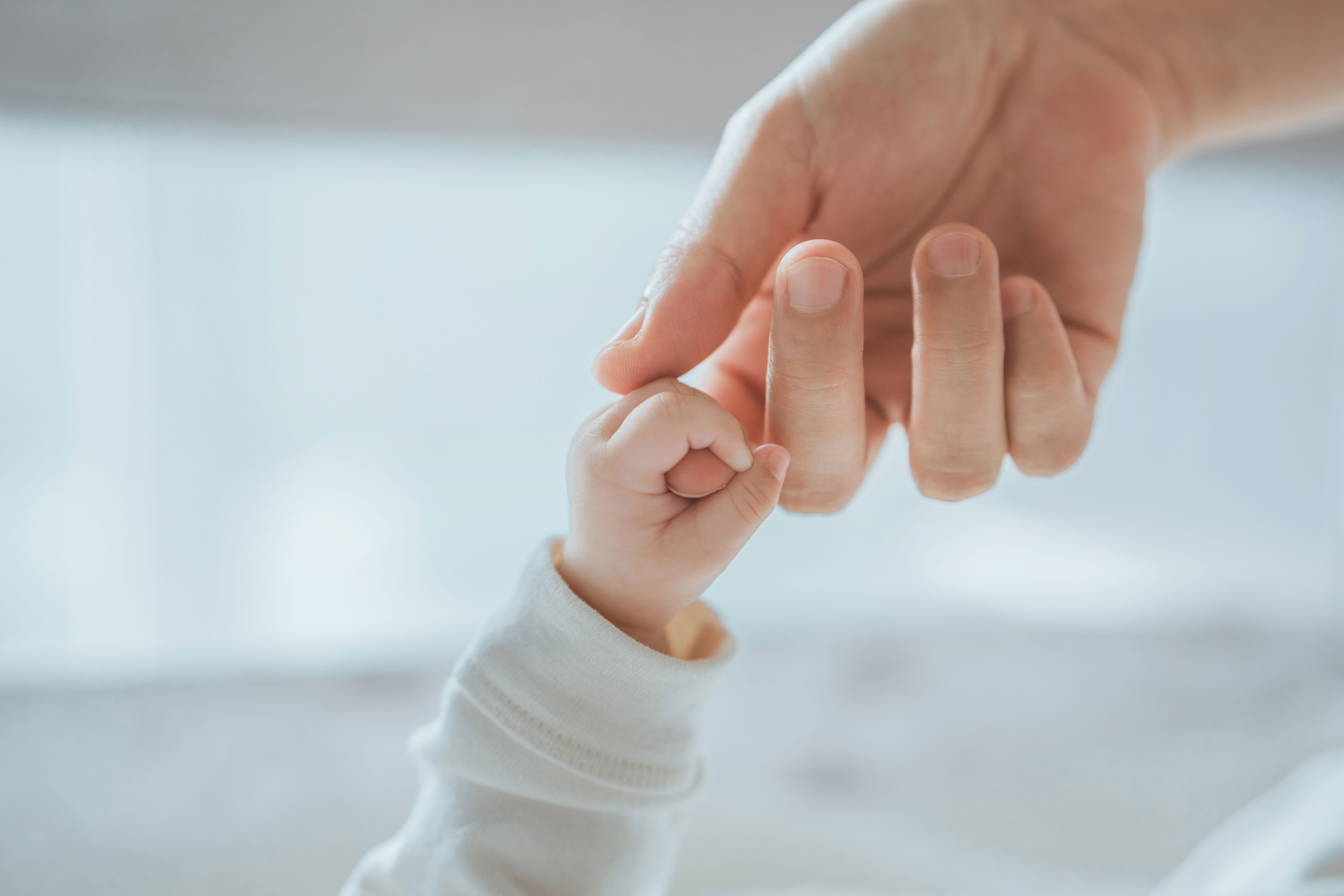 A baby and adult holding hands.