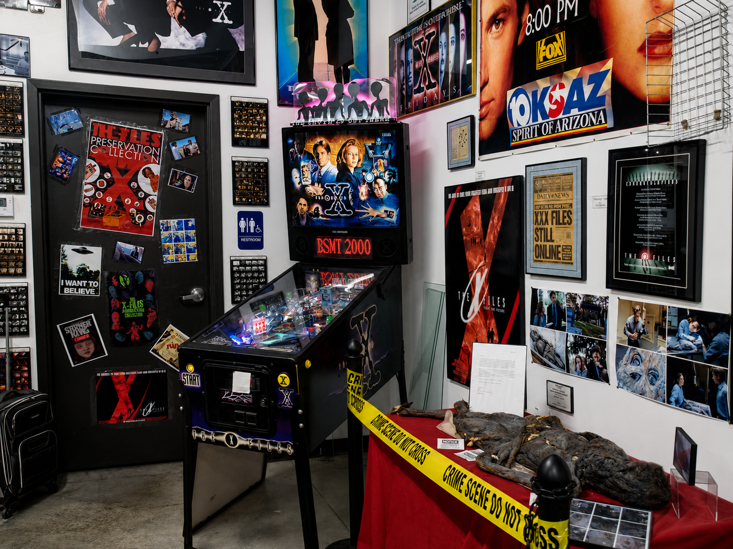 An “X-Files” pinball machine stands among props, photographs and other memorabilia at The X-Files Preservation Collection & Collectibles in Saratoga Springs, N.Y. The museum’s permanent location opened April 30, 2022, with series creator Chris Carter and actor and creature performer Keith Arbuthnot among the special guests. [Photo: S Cobaugh, Aug. 20, 2026]