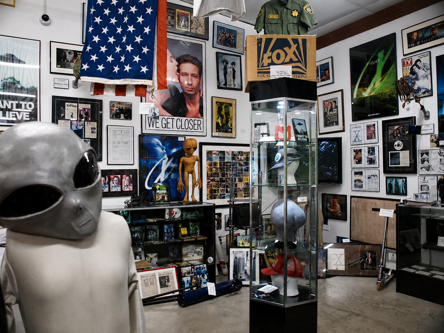 An alien figure stands among costumes, posters, photographs and other memorabilia at The X-Files Preservation Collection & Collectibles in Saratoga Springs, N.Y. The museum describes its holdings as the world’s largest collection of authentic screen-used props, costumes and set dressings from “The X-Files” television series and films. [Photo: D Dymond, Aug. 20, 2026]