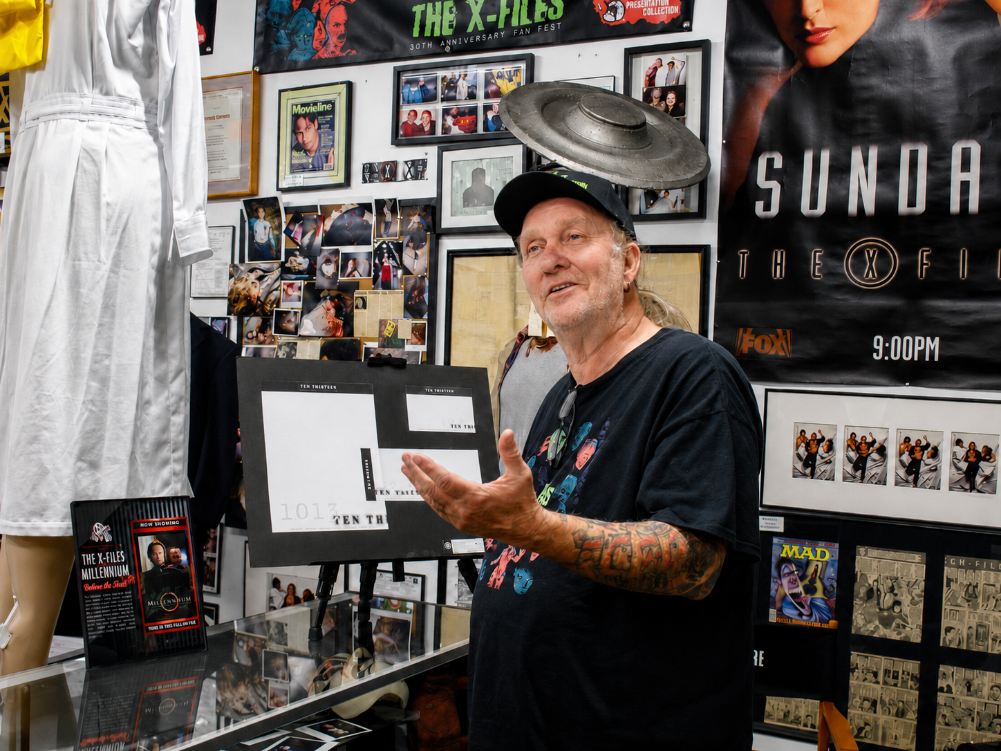 Jim Thornton, co-owner of The X-Files Preservation Collection & Collectibles, discusses artifacts on display at the museum in Saratoga Springs, N.Y. Thornton and co-owner Kelly Anthony have assembled a collection that includes production-used props, costumes, set pieces and other memorabilia from “The X-Files” television series and films. [Photo: S Cobaugh, Aug. 20, 2026]