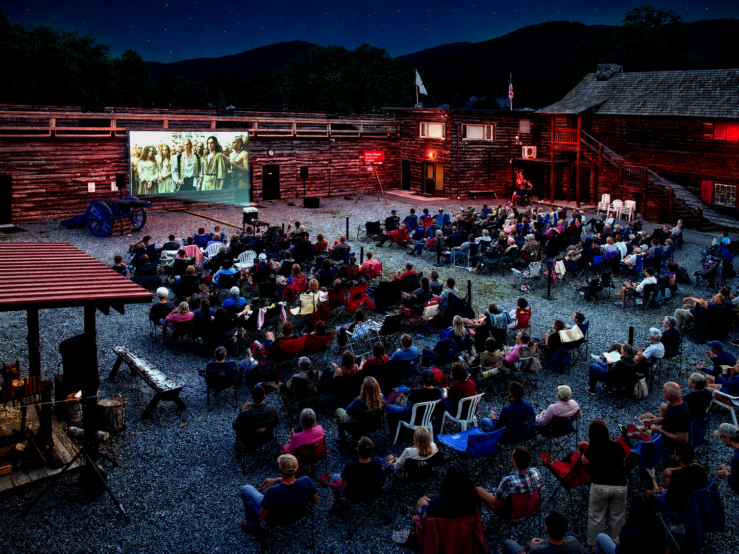 Visitors gather on the parade ground at Fort William Henry in Lake George, N.Y., for an outdoor screening of “The Last of the Mohicans.” The museum’s immersive movie presentations combine the 1992 film with live musket and cannon fire synchronized to the action. The 1757 siege and surrender of Fort William Henry became a central setting in James Fenimore Cooper’s 1826 novel, which marked its 200th anniversary in 2026. [Photo: S Cobaugh, Aug. 22, 2026]