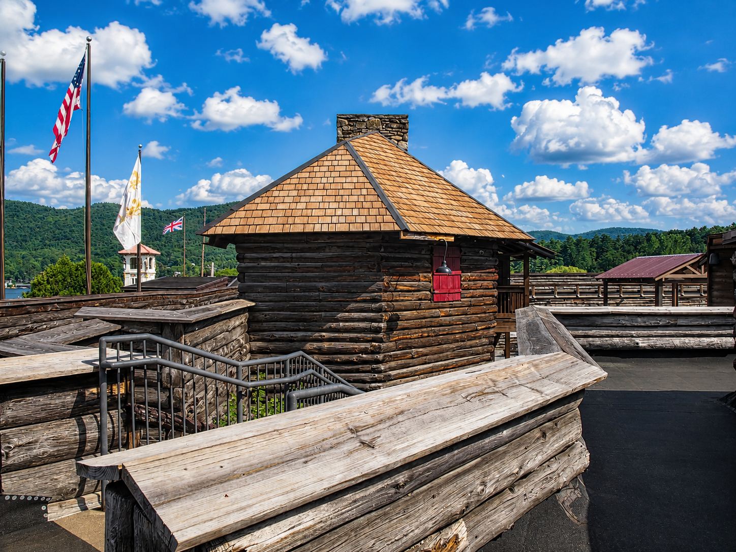 Reconstructed log buildings, ramparts and defensive works are seen inside Fort William Henry in Lake George, N.Y. British military engineer William Eyre designed the original 1755 fort in the Vauban style, using log facings filled with earth to create walls about 30 feet thick. The fort was surrounded by a dry moat on three sides and was designed to accommodate about 400 to 500 soldiers. [Photo: S Cobaugh, Aug. 22, 2026]