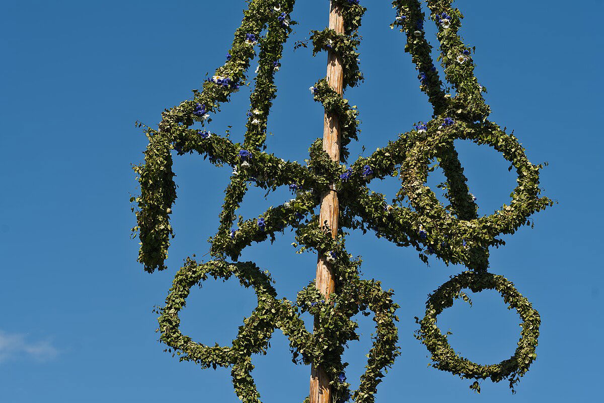 Photograph of Midsommar leaf/vine-covered crowns on the top of a pole.