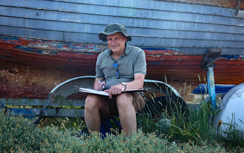 James Weaver. James happily sketching some boats near the end of Coast Road, Mersea. Photo taken by Chrissie Westgate.