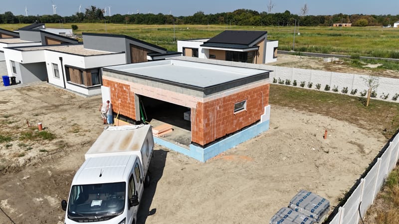 A képen a garázs homlokzatának hőszigetelési és festési munkálatai láthatók. A projekt során korszerű hőszigetelő anyagokat alkalmaztunk, majd esztétikus, időjárásálló kültéri bevonattal láttuk el a felületet, biztosítva a tartósságát.