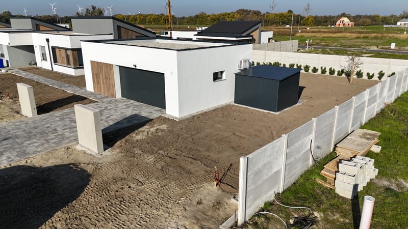 A képen a garázs homlokzatának hőszigetelési és festési munkálatai láthatók. A projekt során korszerű hőszigetelő anyagokat alkalmaztunk, majd esztétikus, időjárásálló kültéri bevonattal láttuk el a felületet, biztosítva a tartósságát.