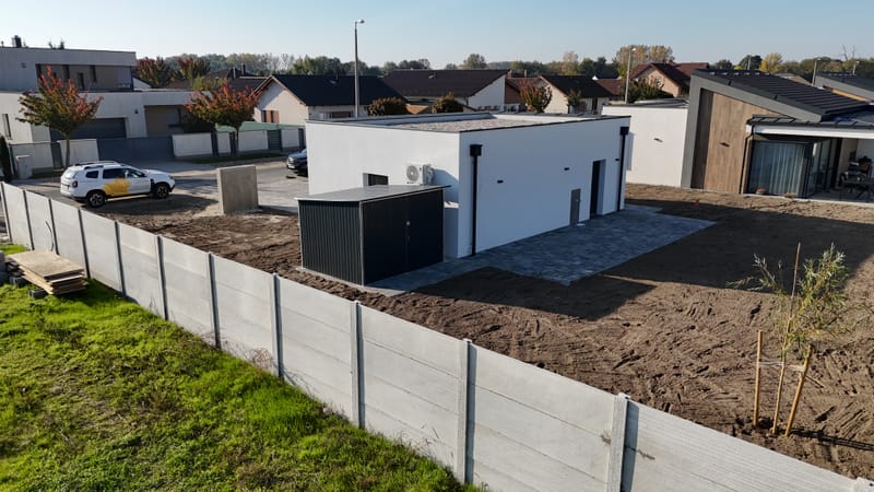 A képen a garázs homlokzatának hőszigetelési és festési munkálatai láthatók. A projekt során korszerű hőszigetelő anyagokat alkalmaztunk, majd esztétikus, időjárásálló kültéri bevonattal láttuk el a felületet, biztosítva a tartósságát.