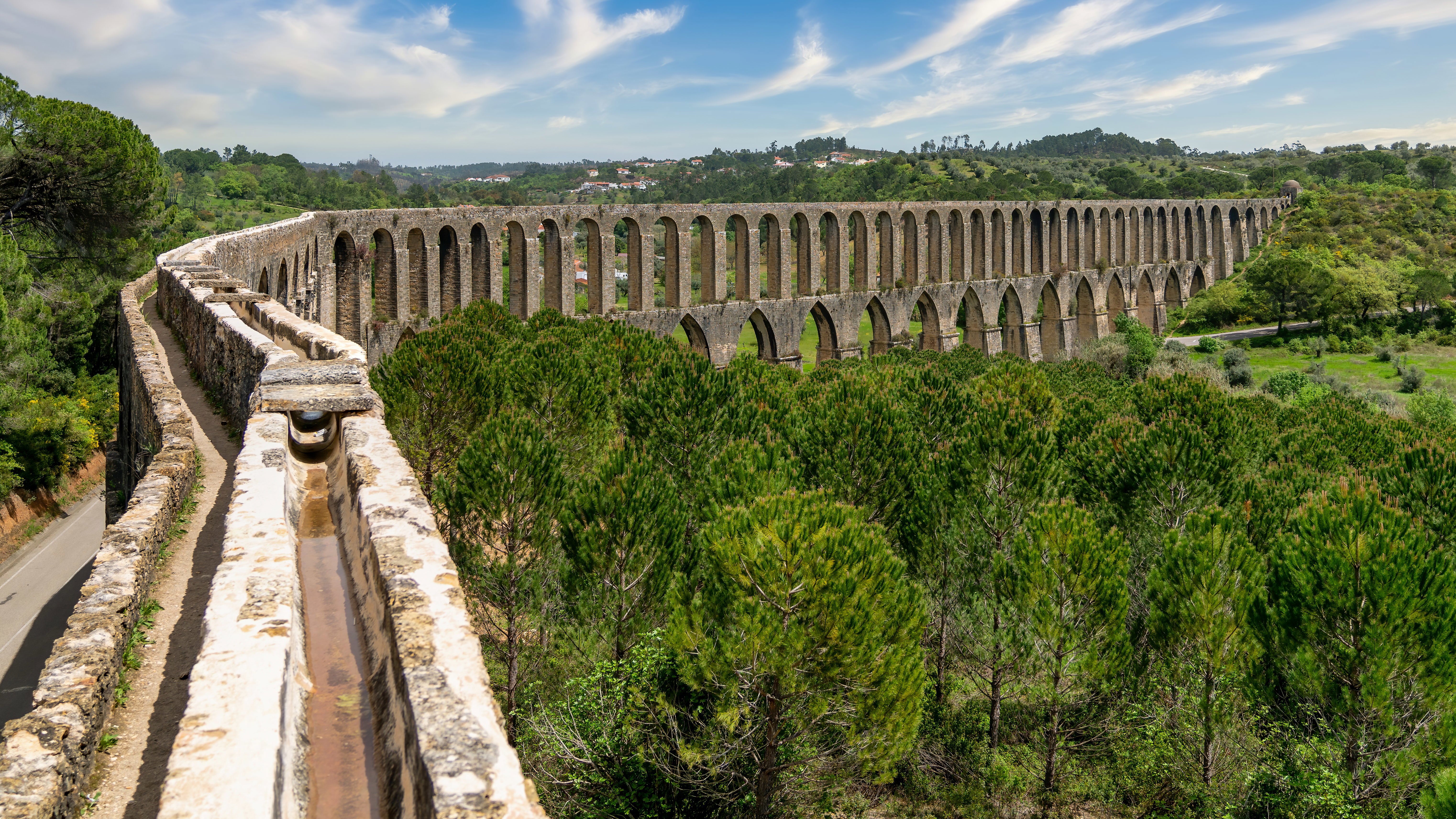 Central Portugal: A historic stone aqueduct running through green pine-covered hills near Tomar in Central Portugal.
