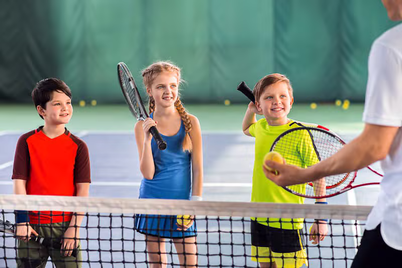 Tennis coach teaching a young child