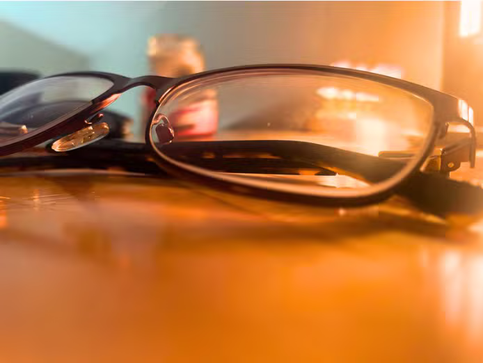 Eyeglasses resting on a table in warm light