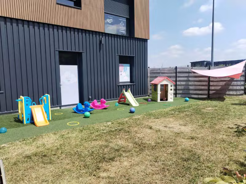 Espace extérieur de la crèche avec aire de jeux sur gazon