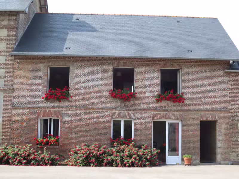 Façade en briques de la ferme avec fenêtres fleuries