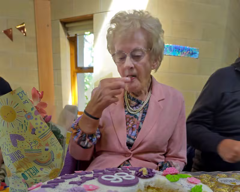 A member of the congregation cutting a birthday cake