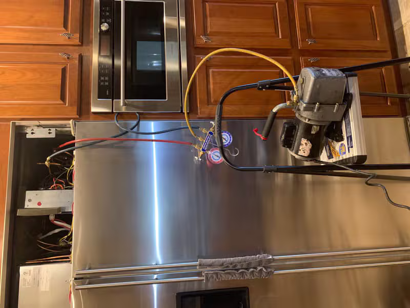 Technician working on a sealed system refrigerator