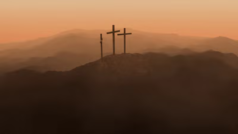 Three crosses on a hill at sunset