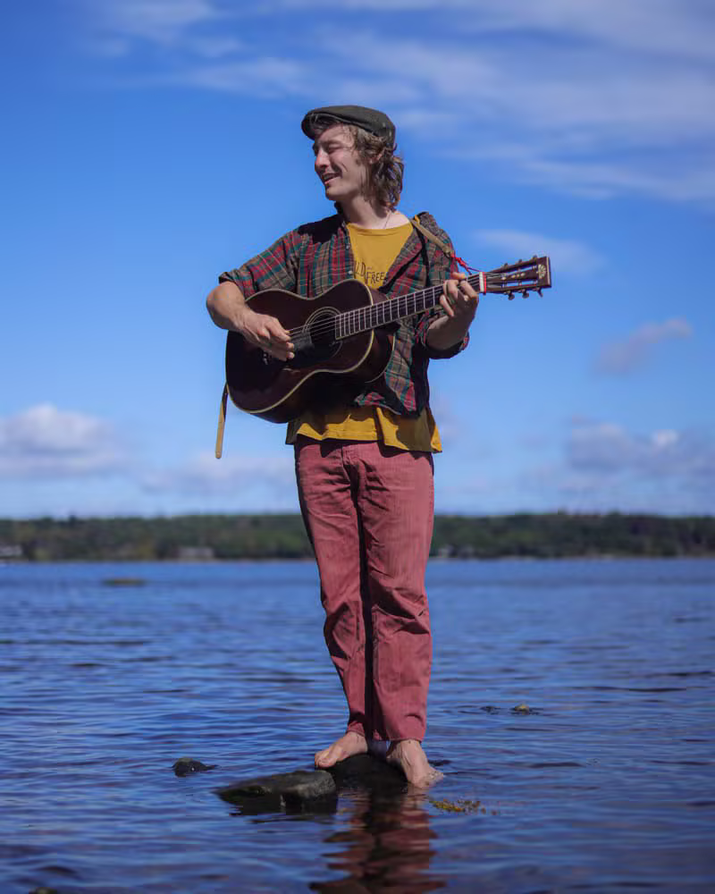 Hunter Hughes playing guitar by the water