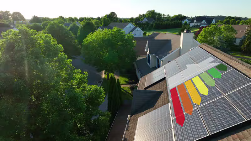 Aerial view of Cambridge homes with rooftop solar panels overlaid with an A to G energy efficiency rating chart