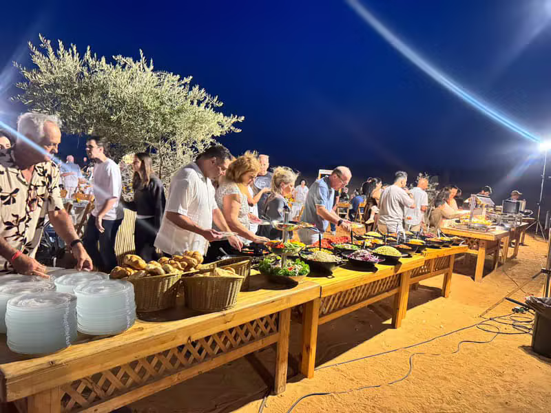 אורחים סביב בופה עשיר ומואר באירוע שטח בלילה