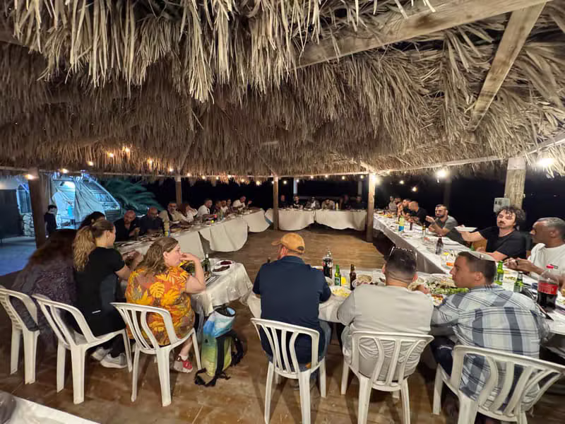 שולחנות אירוח מלאים באורחים תחת סכך עם תאורה חמה