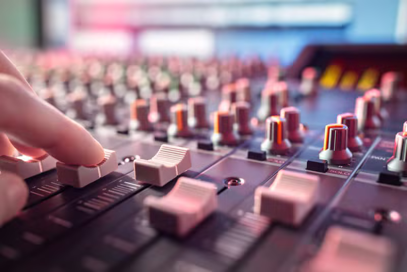 Audio engineer adjusting a mixing board