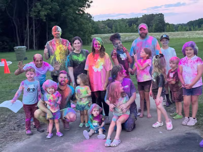 Church community members having fun outdoors covered in colorful powder