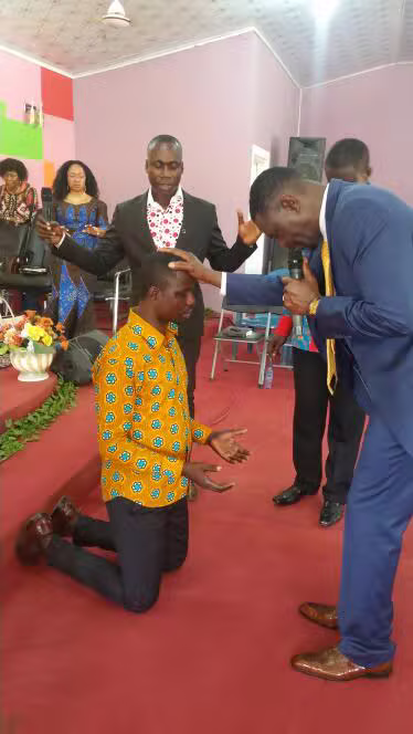 Pastor laying hands in prayer over a kneeling congregation member