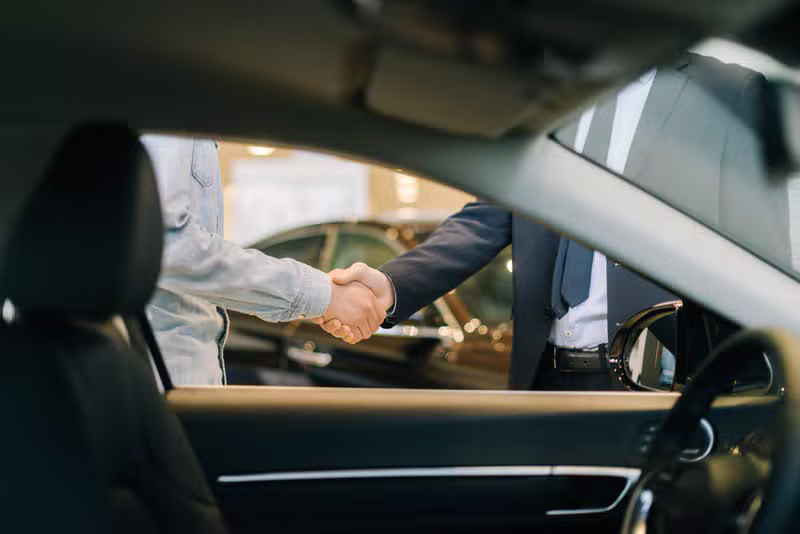 Friendly car salesperson shaking hands with a customer