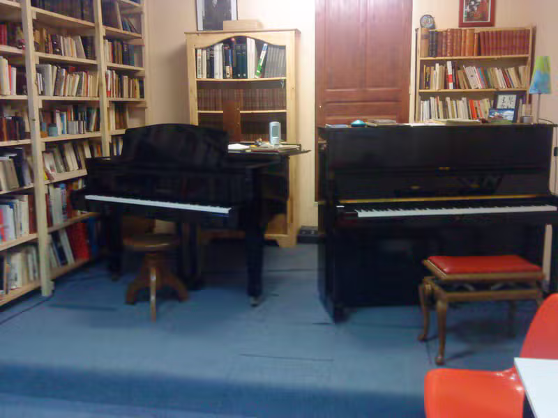 Salle de cours avec un piano à queue et un piano droit