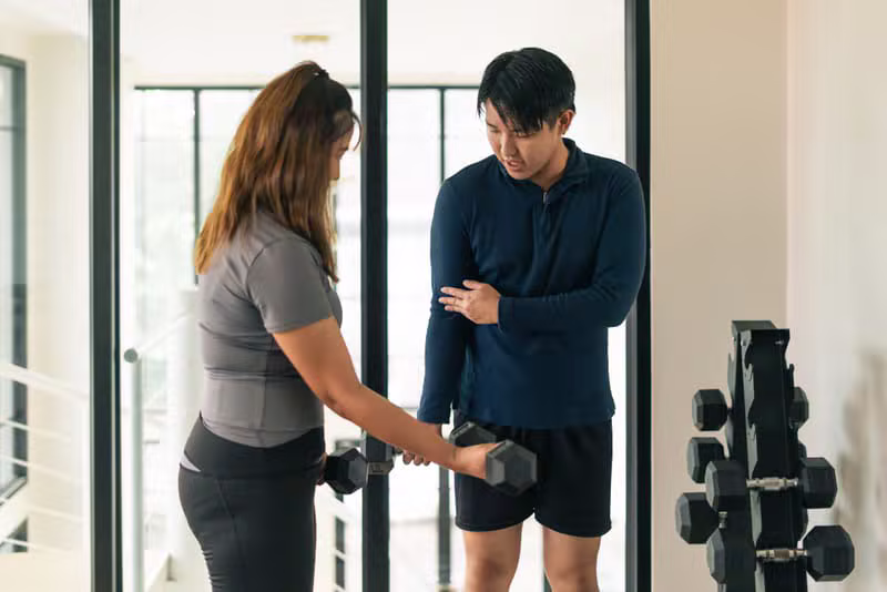Personal trainer assisting a client with weights