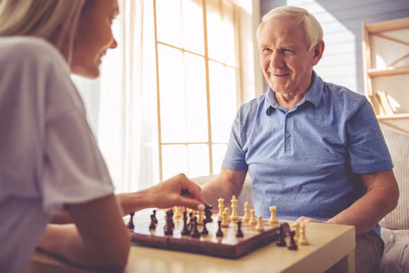 Zorgmedewerker speelt een bordspel met een oudere