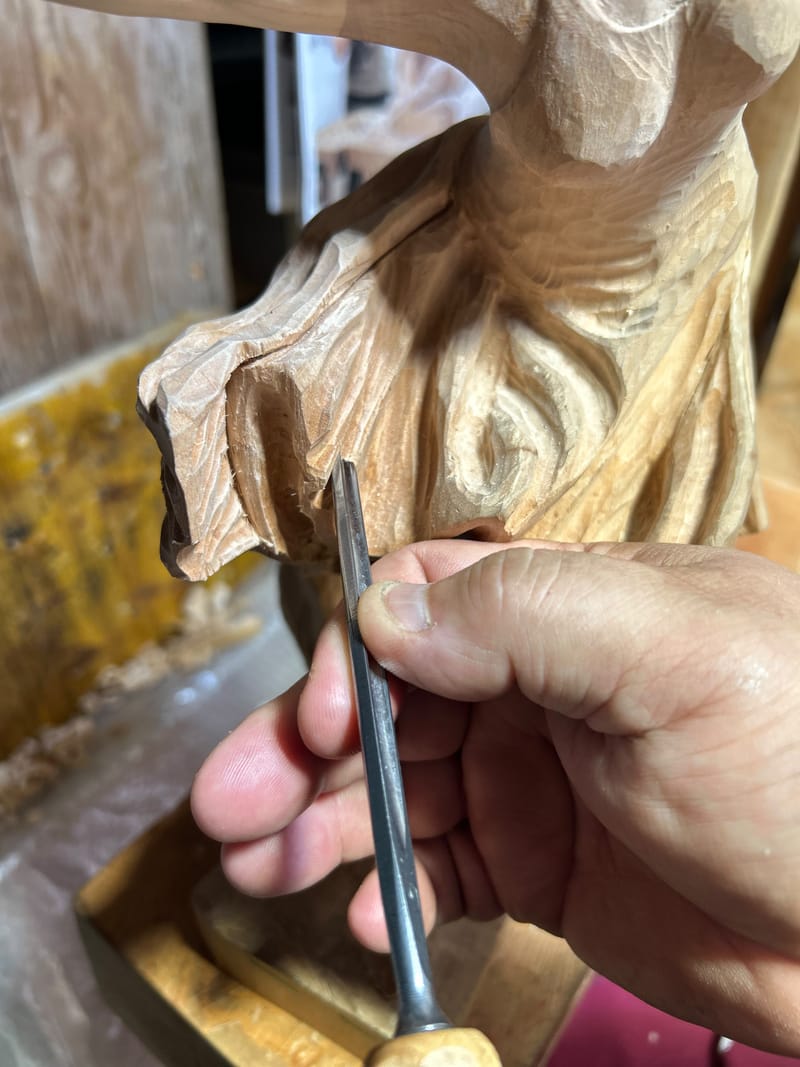 Mani artigiane che scolpiscono il legno con una sgorbia