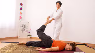 Thai massagem com terapeuta focado e cliente relaxando de olhos fechados