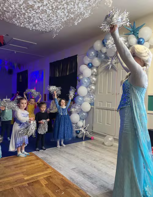 Frozen themed party with a princess character and a balloon arch