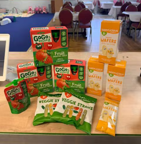 A selection of children's snacks and fruit pouches on the café counter
