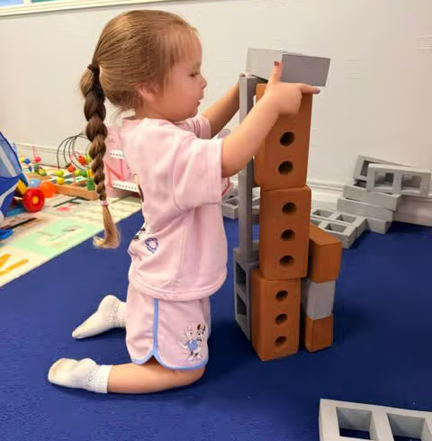 A toddler stacking wooden blocks during play