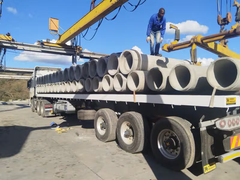 Worker securing concrete pipes on a flatbed trailer