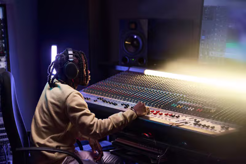 Professional music producer working at a studio mixing console