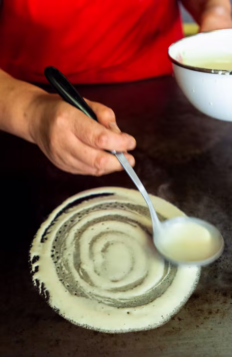 Pouring fresh dosa batter on a hot pan