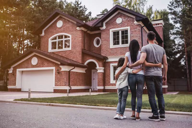 Happy homeowner standing in front of newly painted house