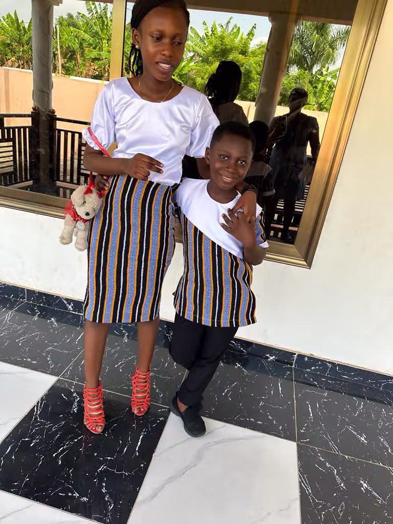 Mother and son wearing matching blue and gold Kente striped African outfits