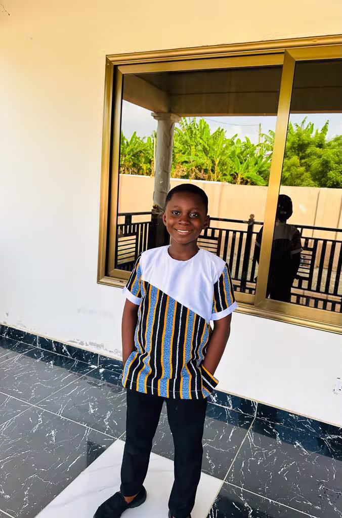 Young boy wearing a blue and gold striped African print panel top